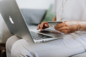 Person using a macbook and holding a credit card